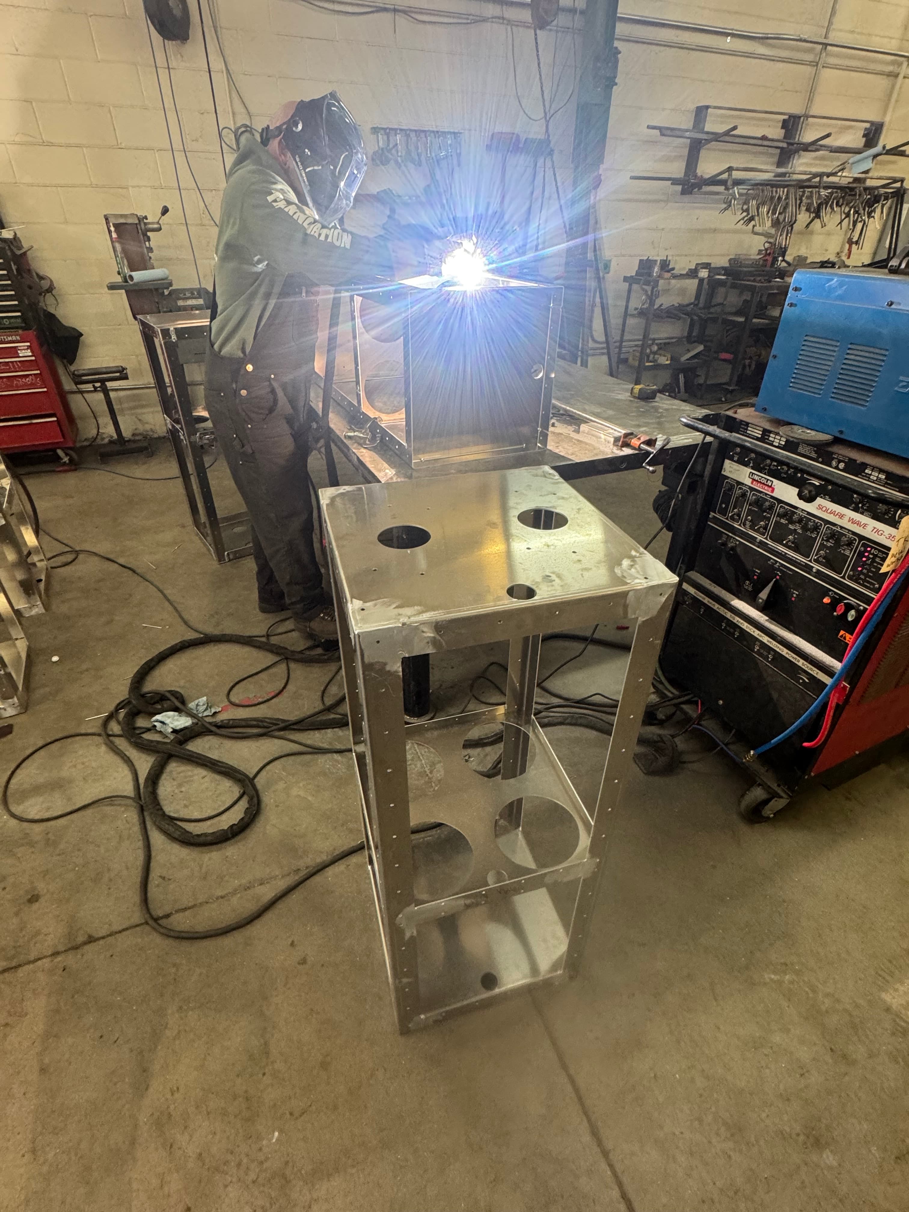 Welding fabrication with arc flash and finished units in background